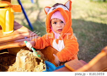 adorable toddler playing in the sandbox. cute child in fox pajamas plays in the sand. portrait of a happy baby adorable toddler playing in the sandbox. cute child in fox pajamas plays in the sand. portrait of a happy baby 81813059