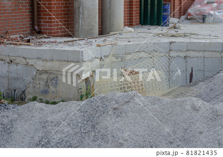 Construction debris and waste at the construction site. Red brick building. Concrete foundation. Construction Industry. Architecture. No people. Construction debris and waste at the construction site. Red brick building. Concrete foundation. Construction Industry. Architecture. No people. 81821435