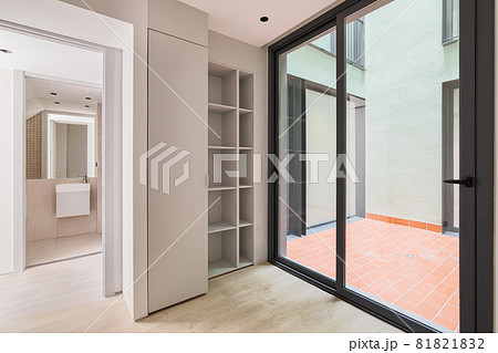 Interior of modern empty room in refurbished apartment with big black frame of windows, wardrobe and view to the bathroom. 81821832