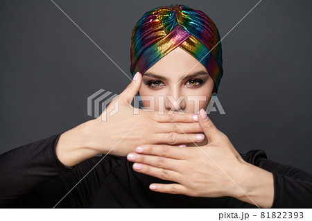 Beautiful woman in turban covering her face with her hands on black background Beautiful woman in turban covering her face with her hands on black background 81822393