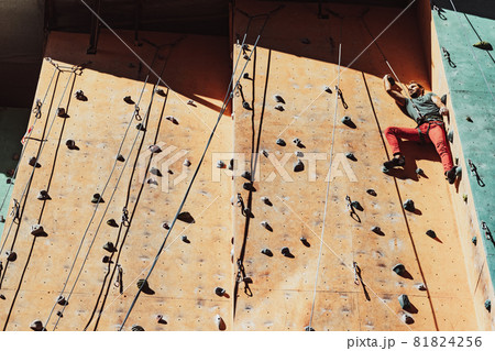 One Caucasian man professional rock climber workouts on climbing wall at training center in sunny day, outdoors. Concept of healthy lifestyle, power, strength, motion. One Caucasian man professional rock climber workouts on climbing wall at training center in sunny day, outdoors. Concept of healthy lifestyle, power, strength, motion. 81824256