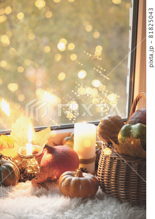 Cozy autumn window sill at home with candles, coffee, pumpkins, garland and fur. 81825043