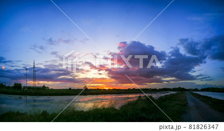 Panorama The pond reflects the light from the orange sun. The pool edge is green and yellow grass. The evening sky before the sunset is colorful. Panorama The pond reflects the light from the orange sun. The pool edge is green and yellow grass. The evening sky before the sunset is colorful. 81826347