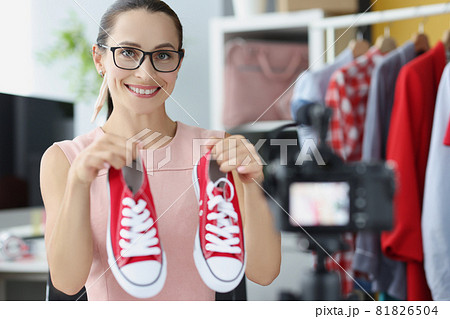 Woman blogger recommends buying red sports shoes in online store closeup Woman blogger recommends buying red sports shoes in online store closeup 81826504