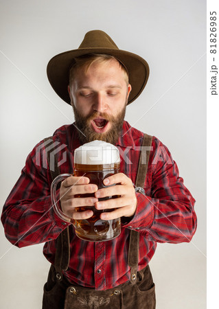 Half-length portrait of bearded man in hat and traditional Bavarian costume holding huge mug, glass of light frothy beer isolated over white background. Flyer Half-length portrait of bearded man in hat and traditional Bavarian costume holding huge mug, glass of light frothy beer isolated over white background. Flyer 81826985