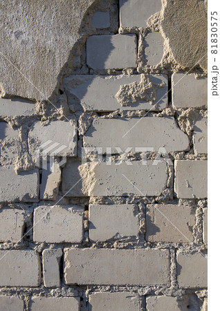Painted in grey white colors old vintage empty brick wall background with Putty. Rustic cemented house stonewall texture with grunge surface. Shabby Building Facade With Damaged Plaster Painted in grey white colors old vintage empty brick wall background with Putty. Rustic cemented house stonewall texture with grunge surface. Shabby Building Facade With Damaged Plaster 81830575
