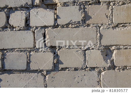 Painted in grey white colors old vintage empty brick wall background with copy space. Rustic cemented house stonewall texture with grunge surface. Shabby Building Facade With Damaged Plaster Painted in grey white colors old vintage empty brick wall background with copy space. Rustic cemented house stonewall texture with grunge surface. Shabby Building Facade With Damaged Plaster 81830577