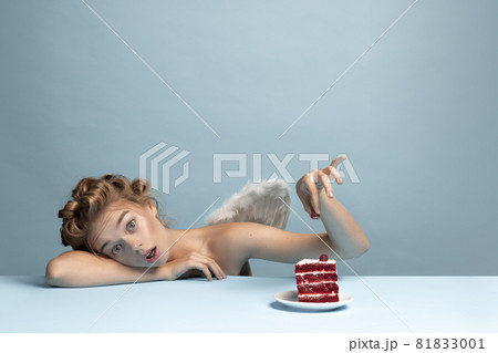 Portrait of young beautiful girl in image of angel with wings sitting isolated on blue gray studio background. Concept of beauty, purity, tenderness, inner world 81833001