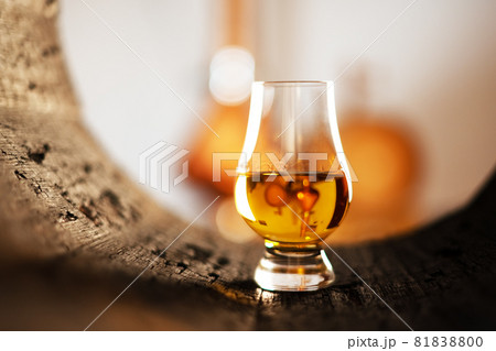 A glass of whiskey in oak barrel A glass of whiskey in oak barrel 81838800