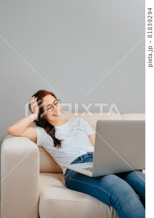 A woman watches online movies via a laptop at home. 81839294