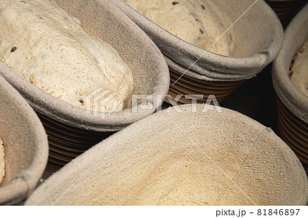 Uncooked bread dough with sprinkles in wooden wicker forms covered with cloth. Craft bread making Uncooked bread dough with sprinkles in wooden wicker forms covered with cloth. Craft bread making 81846897