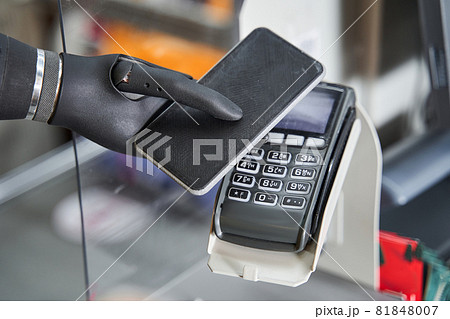 Woman with artificial limb paying contactless by smartphone Woman with artificial limb paying contactless by smartphone 81848007