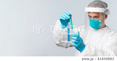 Covid-19, preventing virus, healthcare workers and vaccination concept. Tech lab doctor in clinic wearing personal protective equipment working over vaccine, looking at test-tubes samples 81849883
