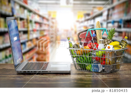 Grocery food buying online and delivery concept. Shopping basket full of food  and laptop on the shelf of supermarket. 81850435
