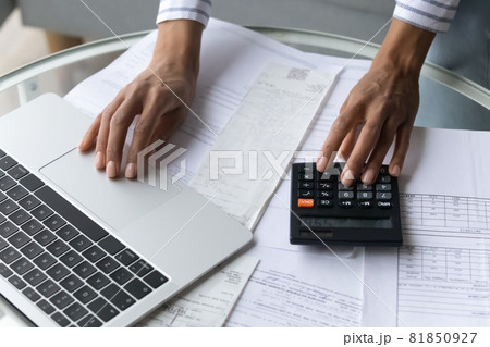 Black female hands using calculator and laptop at home office 81850927