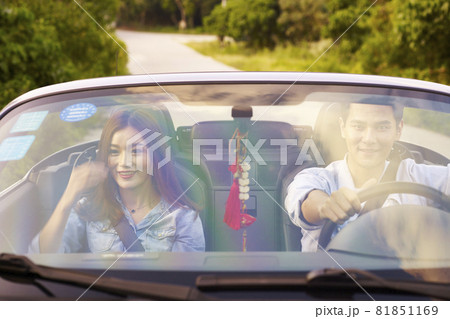 young asian couple enjoying a ride in a convertible sports car young asian couple enjoying a ride in a convertible sports car 81851169