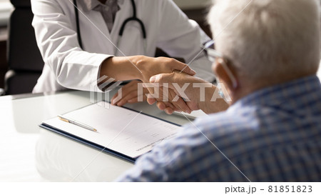Senior man visiting doctor, shaking hands with young female therapist 81851823