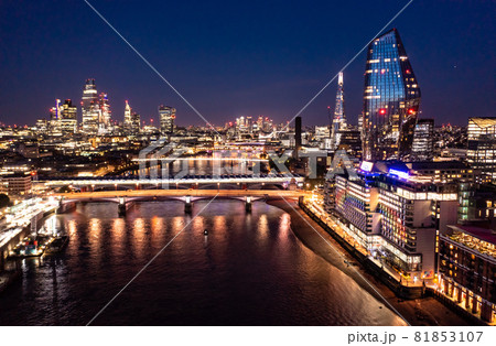 Night view of the beautiful London city with urban architectures bridge at distance with skyscrapers and small buildings around ocean water Night view of the beautiful London city with urban architectures bridge at distance with skyscrapers and small buildings around ocean water 81853107