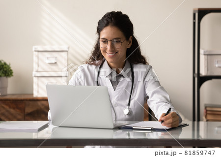 Happy young female GP doctor using laptop, making video call 81859747