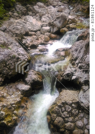 Cold clean water flows over the rocks in the mountains. 81861124