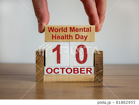 Male hand puts a block with the inscription 'World Mental Health Day' on cubes with the date october 10. Wooden table. Beautiful white background, copy space. 81862955
