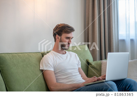 Young bearded man working on a laptop and looking involved 81863365