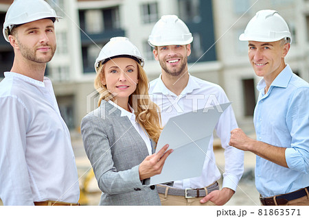 Confident building inspector with a document and builders looking ahead 81863571