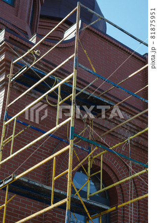 Yellow scaffolding in front of the red brick building. Construction Industry. Architecture. View from bottom to top. Yellow scaffolding in front of the red brick building. Construction Industry. Architecture. View from bottom to top. 81875951
