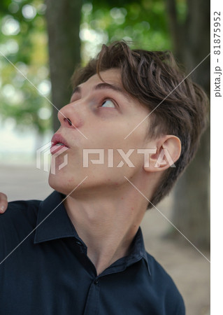 Unusual Portrait of a surprised young man. Young adult in black shirt looking up and away. Daytime. Selective Focus Unusual Portrait of a surprised young man. Young adult in black shirt looking up and away. Daytime. Selective Focus 81875952