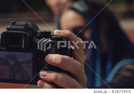 A young woman and a man taking selfies with a DSLR camera. Heterosexual couple in front of the running tracks at the stadium. Female with blue pigtails. Lifestyle. Selective focus. A young woman and a man taking selfies with a DSLR camera. Heterosexual couple in front of the running tracks at the stadium. Female with blue pigtails. Lifestyle. Selective focus. 81875959