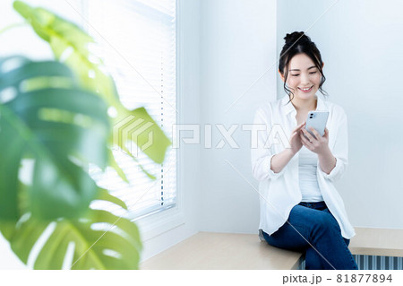 リビングでスマホを使う若い女性 81877894