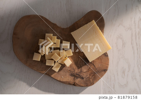 Small block of aged cheese sliced in small pieces on wood board Small block of aged cheese sliced in small pieces on wood board 81879158