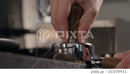 tamping fresh ground coffee in basket of bottomless portafilter 81879431