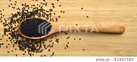 Dry black cumin in wooden spoon, on bamboo cutting board 81881580