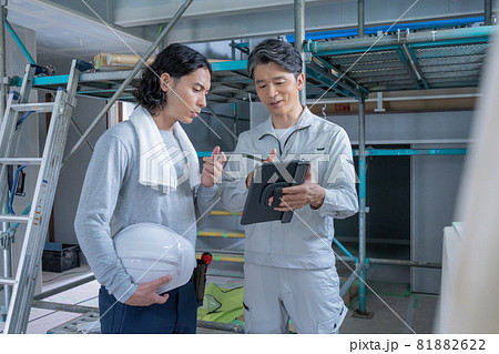 建築現場でタブレットを見ながら会話する現場監督と大工さん2人 建築現場でタブレットを見ながら会話する現場監督と大工さん2人 81882622