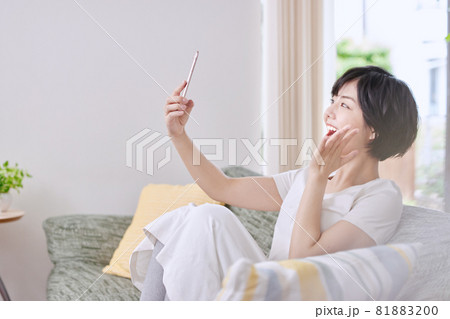 ソファでスマホを見る若い女性 81883200