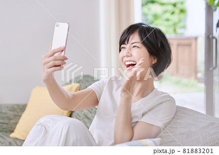 ソファでスマホを見る若い女性 ソファでスマホを見る若い女性 81883201