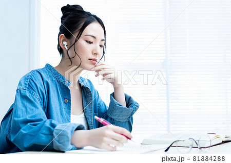 イヤホンをして勉強する若い女性 イヤホンをして勉強する若い女性 81884288