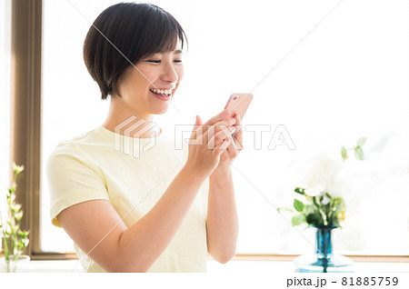 窓際でスマホを見る女性 81885759