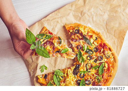 Pizza and hand close up over white background Pizza and hand close up over white background 81886727