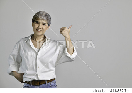 Asian woman pointing fingers up at empty copy space for text isolated on white background Asian woman pointing fingers up at empty copy space for text isolated on white background 81888254