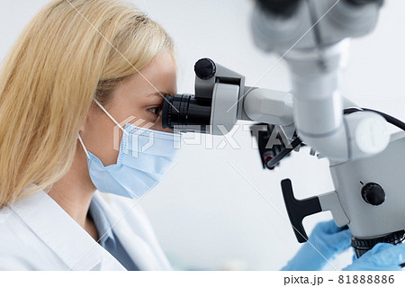 Female dentist looking at dental microscope, innovative dental equipment 81888886
