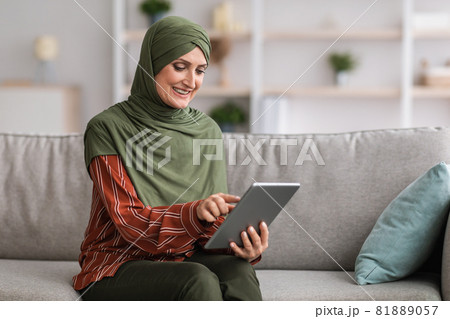 Muslim Lady Using Digital Tablet Browsing Internet Sitting At Home 81889057