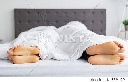 Sexual problems. Young guy and his girlfriend lying apart with their backs to each other in bed, closeup of feet 81889109