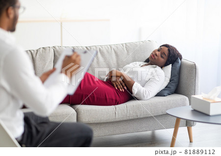 Sad young black woman lying on couch at psychologist's office Sad young black woman lying on couch at psychologist's office 81889112