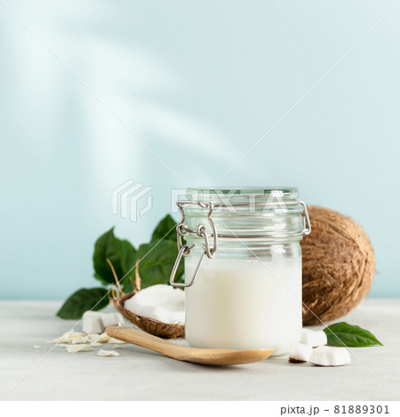 Coconut oil in jar with fresh coconut and tropical leaf shadow, square composition 81889301
