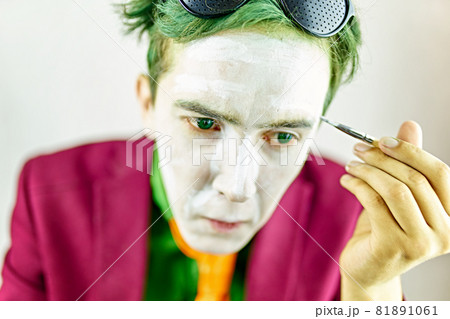Cosplayer guy paints his face with brush. Cosplayer guy paints his face with brush. 81891061