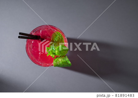 closeup of red strawberry cocktail drink with mint in glass on grey background closeup of red strawberry cocktail drink with mint in glass on grey background 81891483