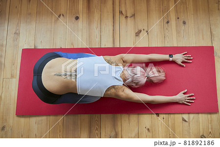 Lady with large tattoo in tracksuit does balasana on wooden floor Lady with large tattoo in tracksuit does balasana on wooden floor 81892186
