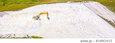 Yellow excavator digs stone chalk 81892415